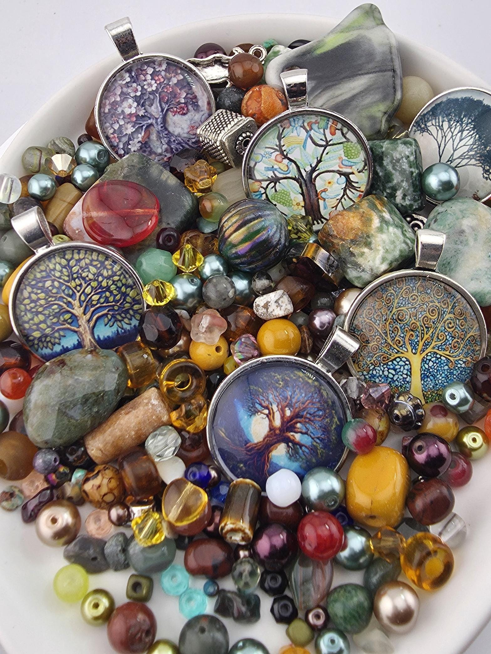 A plate filled with various colorful beads, charms, and glass pieces, including pendants and beads in different shapes and sizes.