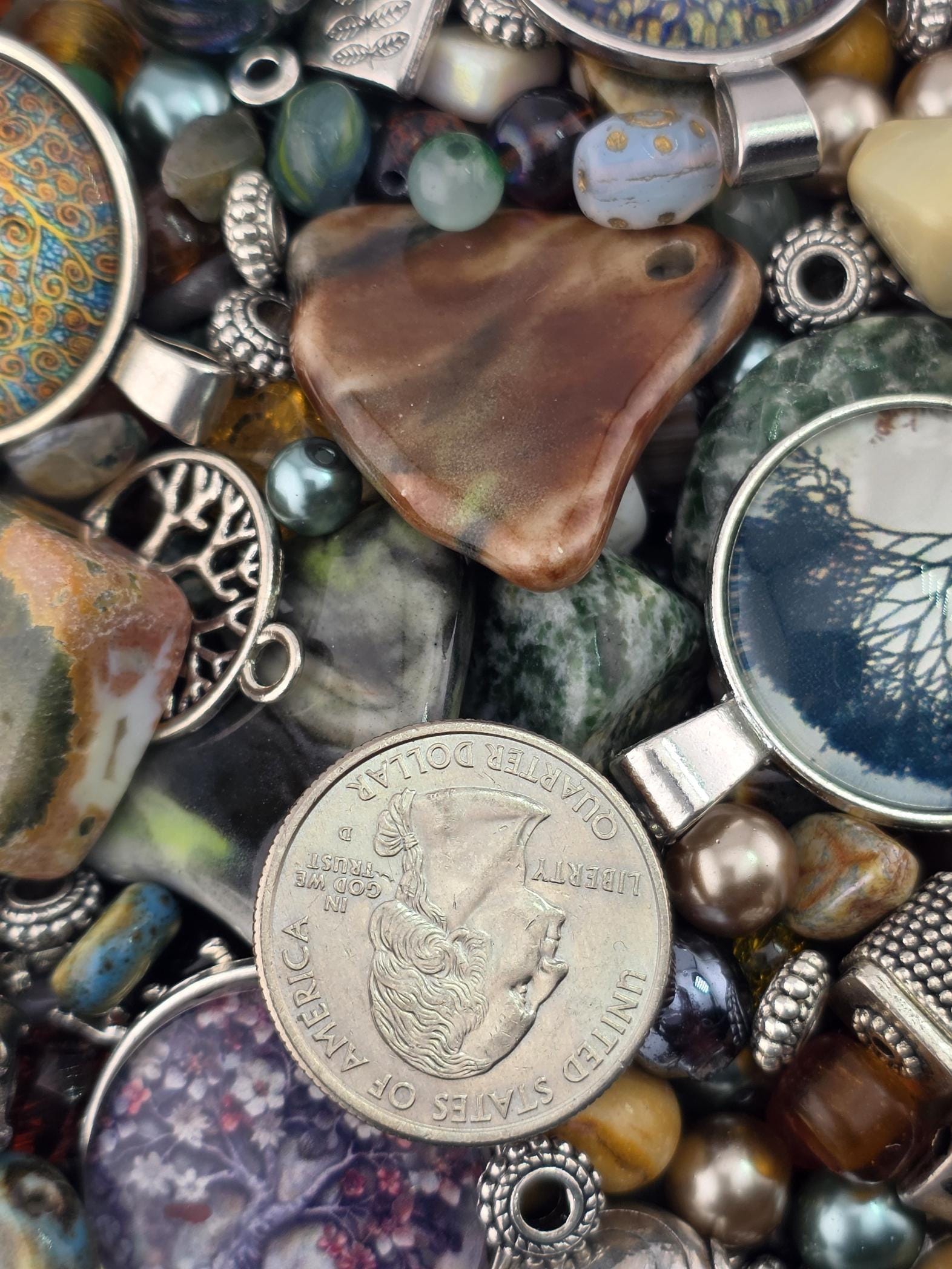 a variety of colorful beads, charms, and a United States quarter coin, creating a visually appealing and diverse collection of jewelry and currency.