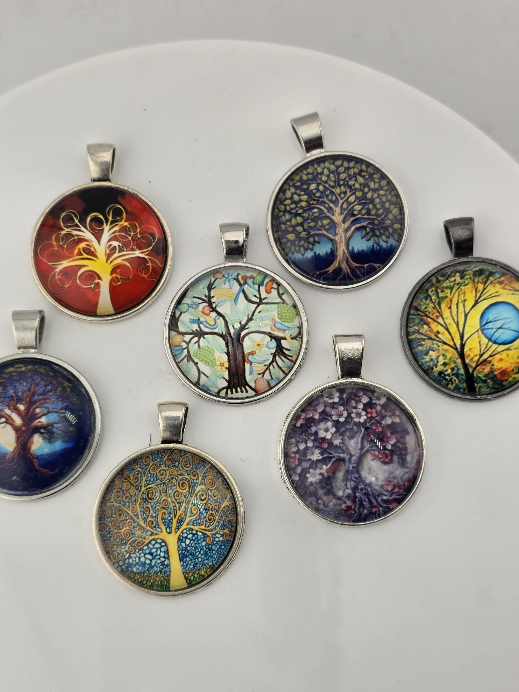 a collection of seven pendant charms, each with a unique tree design, arranged in a circular pattern.