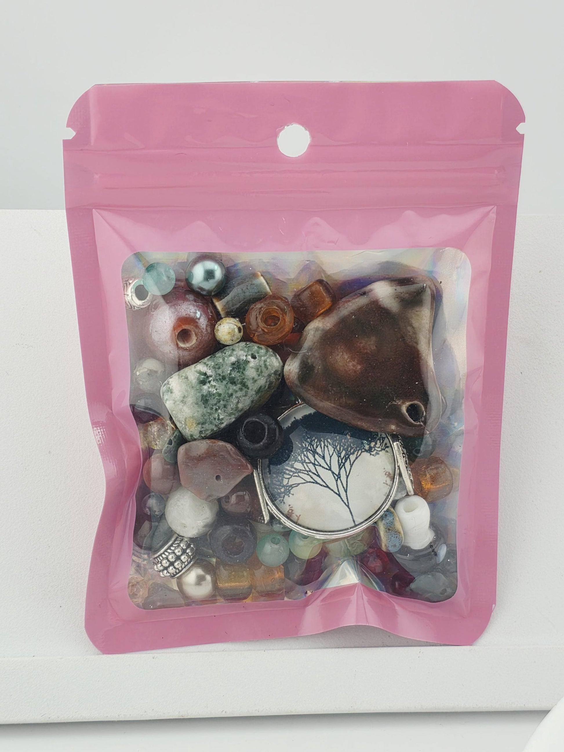 A pink plastic bag containing various colorful beads, stones, and other small objects.