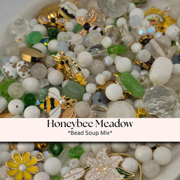 A close-up image of a bowl filled with various beads, charms, and other decorative items, including a bee and a flower.