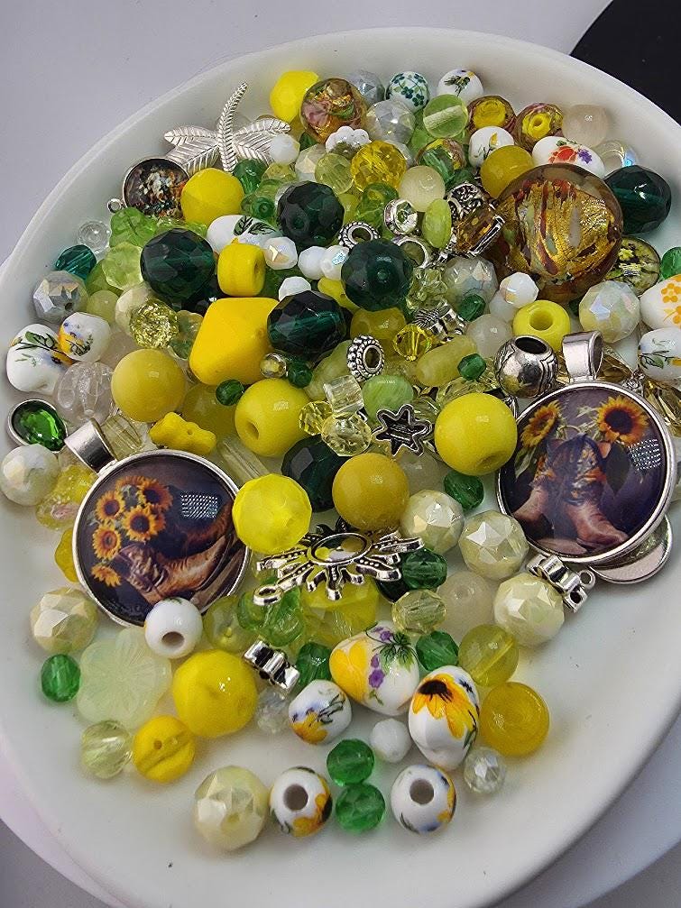 A white plate filled with a variety of colorful beads, charms, and other decorative items.