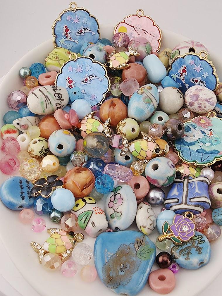 The image is a collection of various colorful beads, charms, and trinkets arranged on a white surface.
