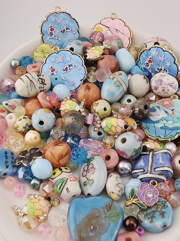 The image is a collection of various colorful beads, charms, and trinkets arranged on a white surface.