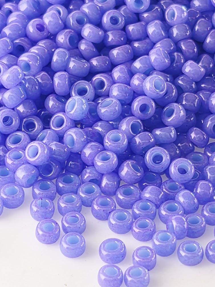 a large pile of small, round, purple beads scattered across a white background.