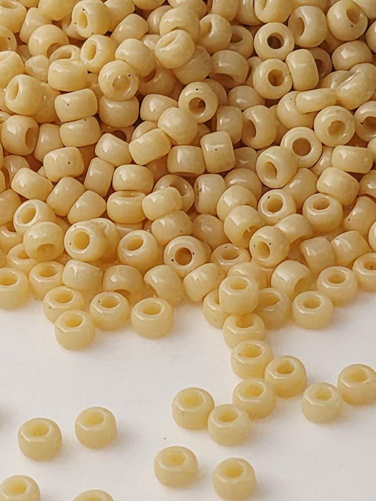 a pile of small, round beads in various shades of yellow, scattered on a white surface.