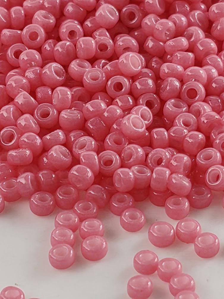 a large pile of pink beads scattered on a white surface.