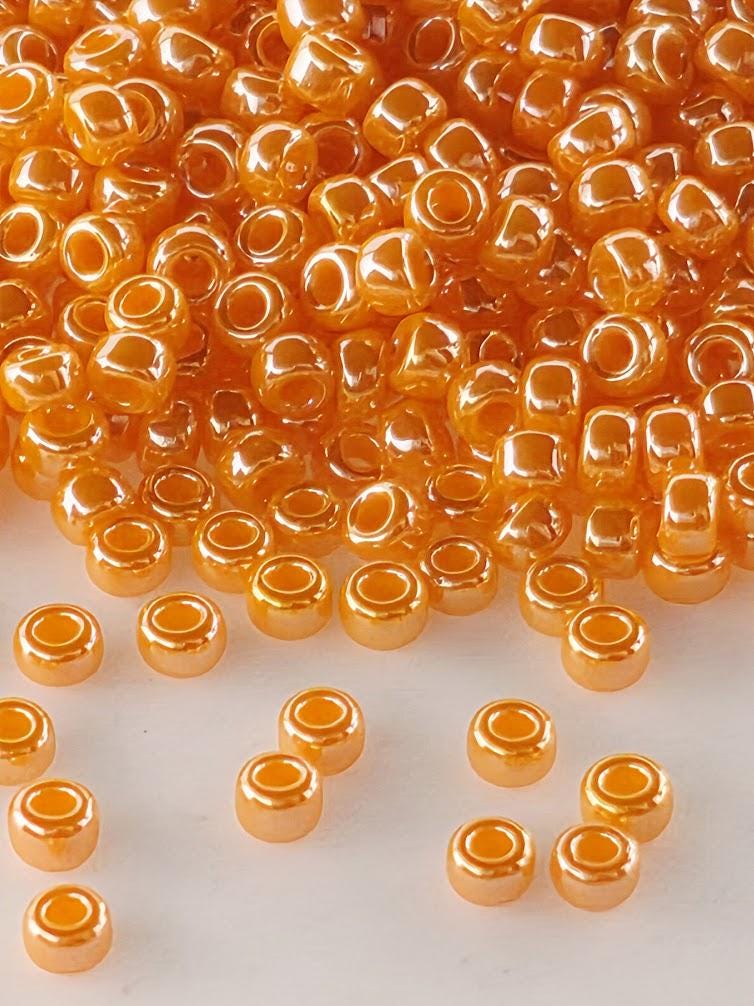 a large pile of small, round, orange beads scattered on a white surface.