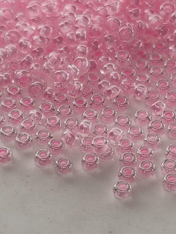 a collection of small, clear glass beads in various shades of pink, scattered across a white surface.