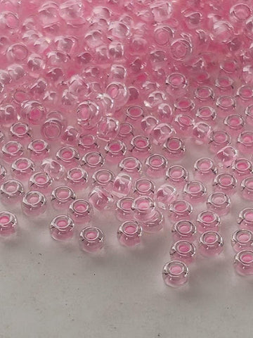a collection of small, clear glass beads in various shades of pink, scattered across a white surface.