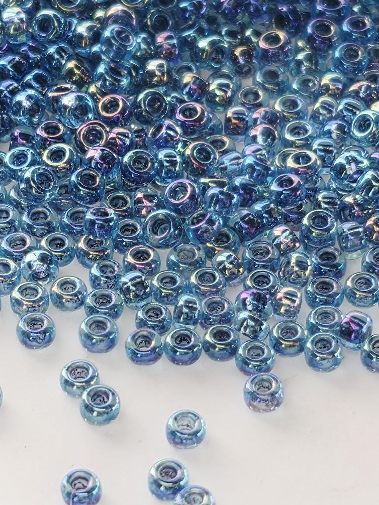 a large number of small, round beads in various shades of blue, scattered across a white background.