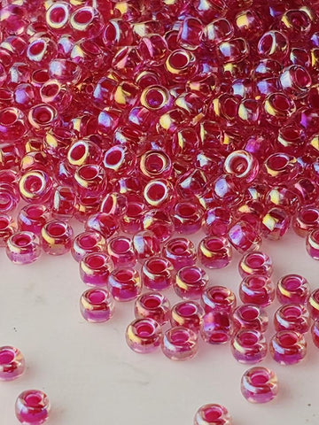a large pile of small, clear beads in shades of pink and red, scattered across a surface.