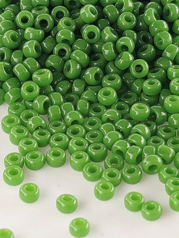 a large pile of green beads, with some of the beads scattered on the floor.