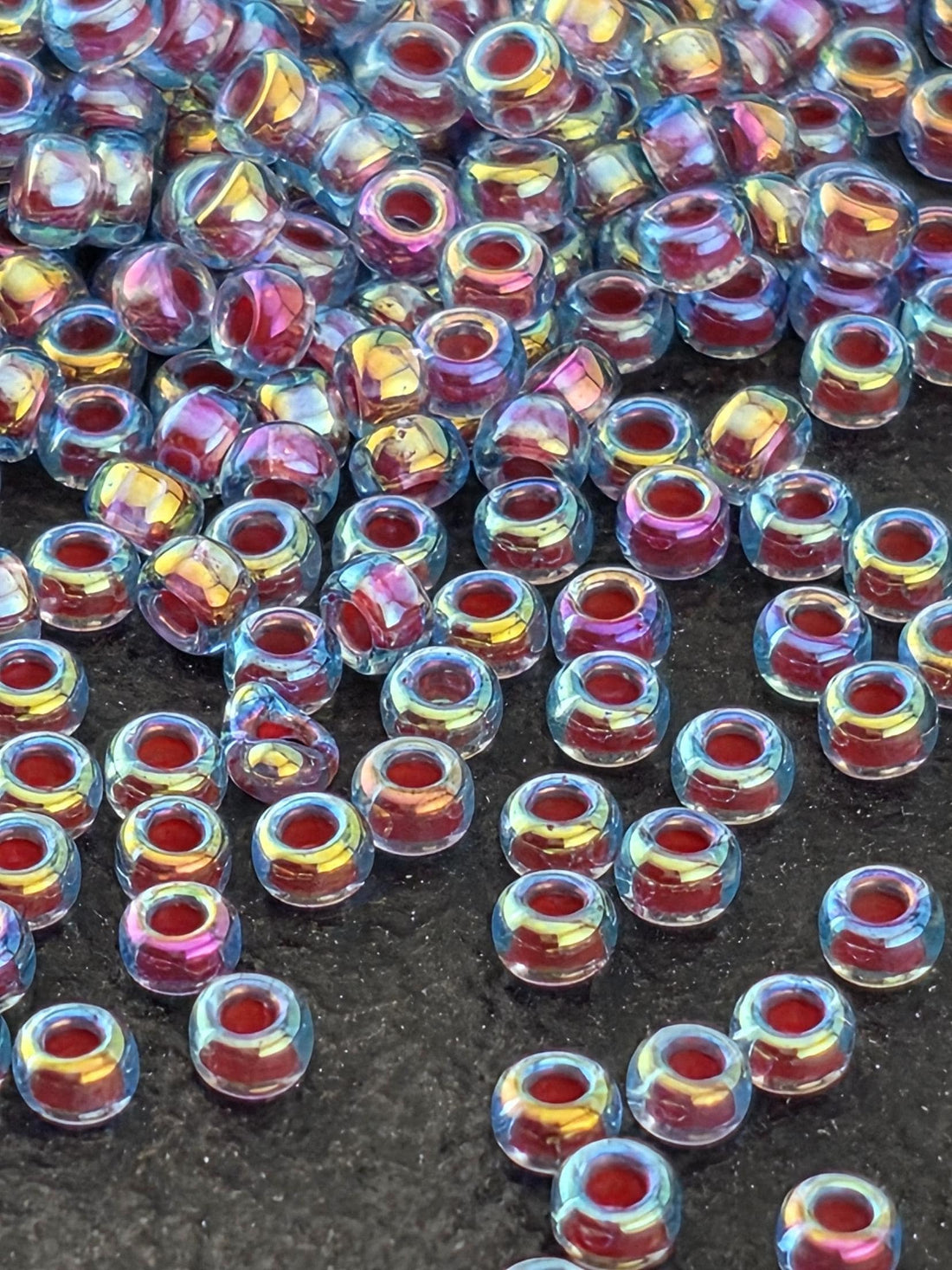 a collection of small, clear beads in various colors, including shades of blue, pink, and purple, scattered across a white surface.