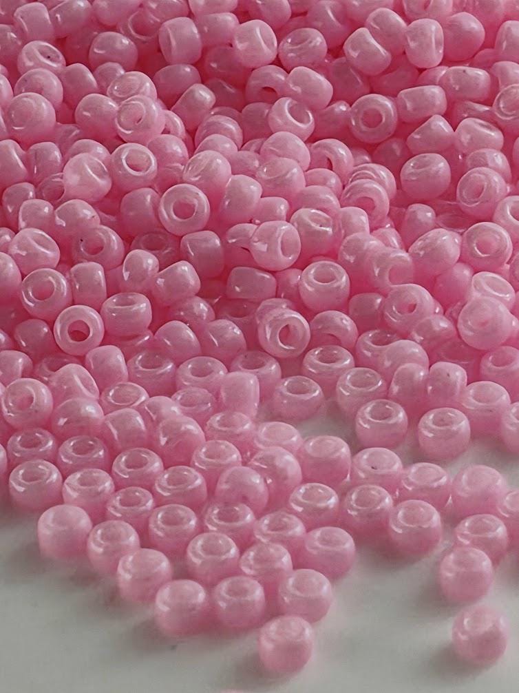 a large pile of small, round, pink beads scattered on a surface.