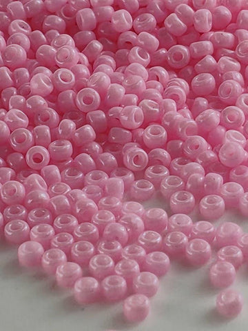 a large pile of small, round, pink beads scattered on a surface.