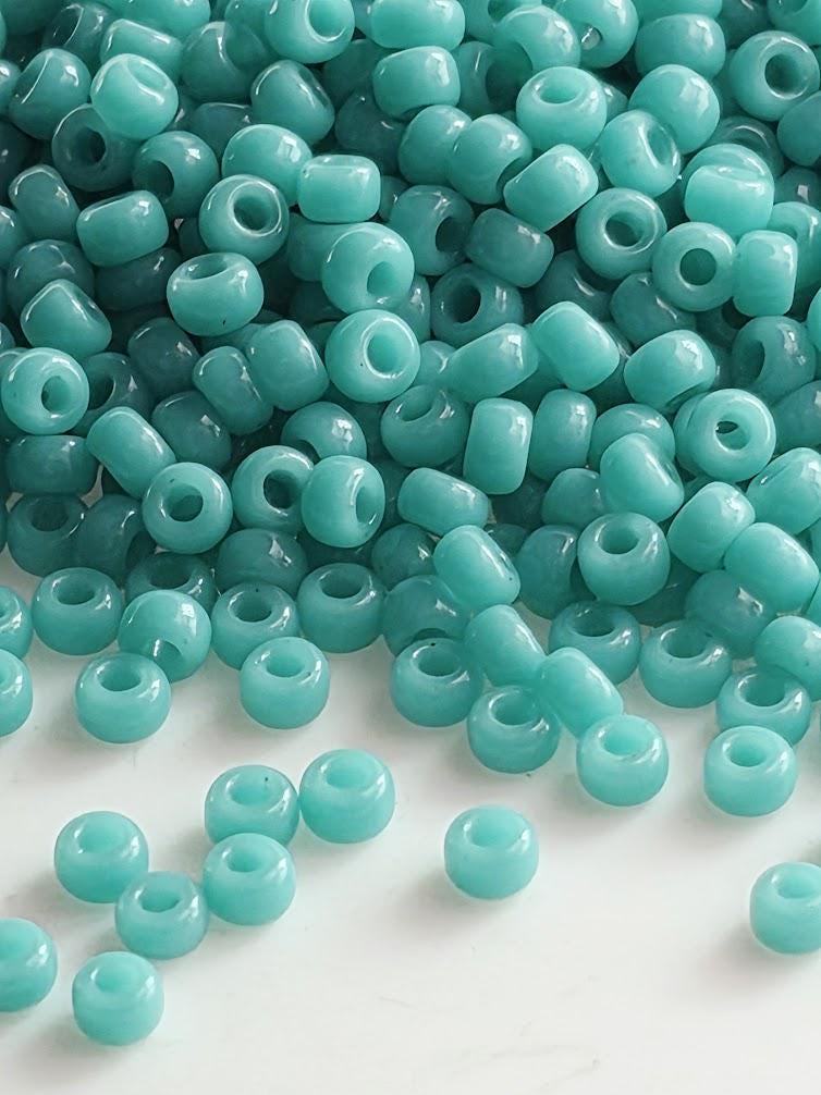a large pile of turquoise-colored beads scattered on a white surface.