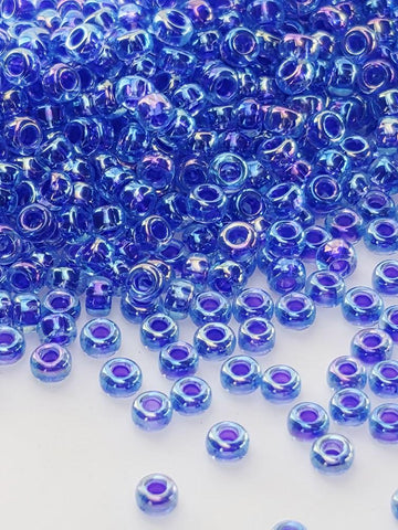 a large pile of small, round, blue beads scattered across a white background.