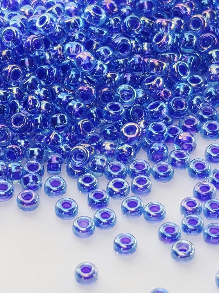 a large pile of small, round, blue beads scattered across a white background.