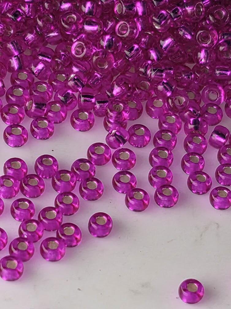 numerous small, round, purple beads scattered across a white background.