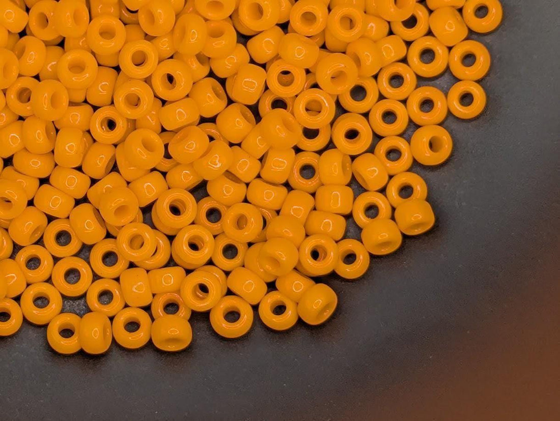 a large pile of bright orange beads scattered across a white surface.