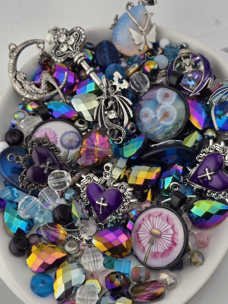 The image is a collection of various colorful beads, charms, and trinkets arranged in a bowl or container.