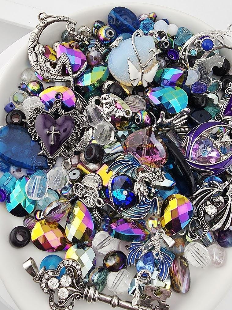 The image is a collection of various colorful beads, charms, and jewelry pieces, including gemstones, pearls, and metalwork, arranged on a white surface.