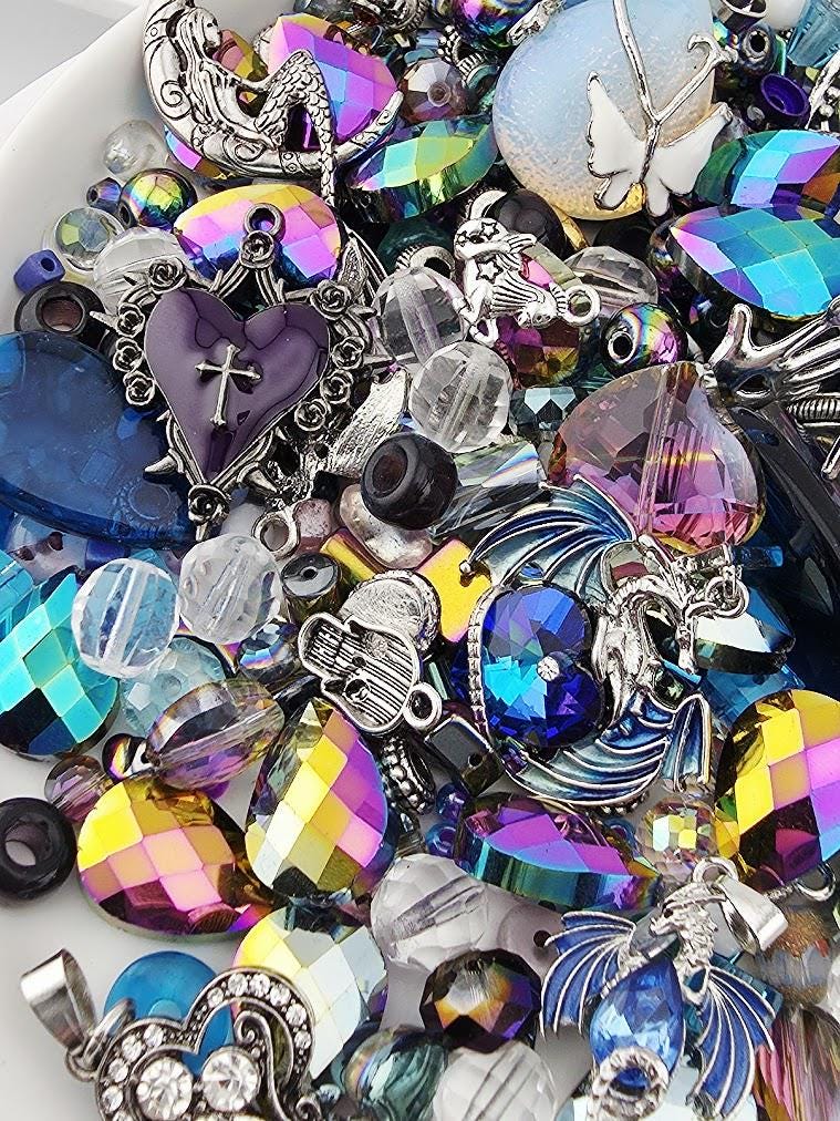 The image is a colorful assortment of various beads, charms, and trinkets, including gemstones, pearls, and metalwork, all arranged together in a visually appealing manner.