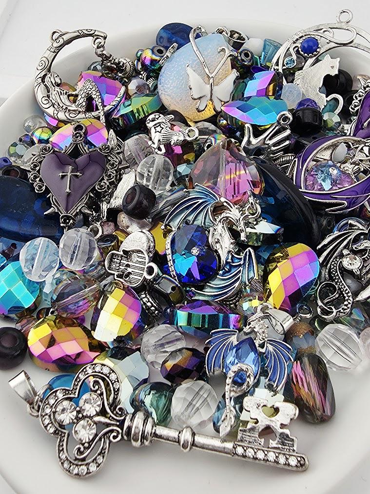 The image is a collection of various colorful and ornate jewelry pieces, including gemstones, charms, and pendants, arranged on a white surface.
