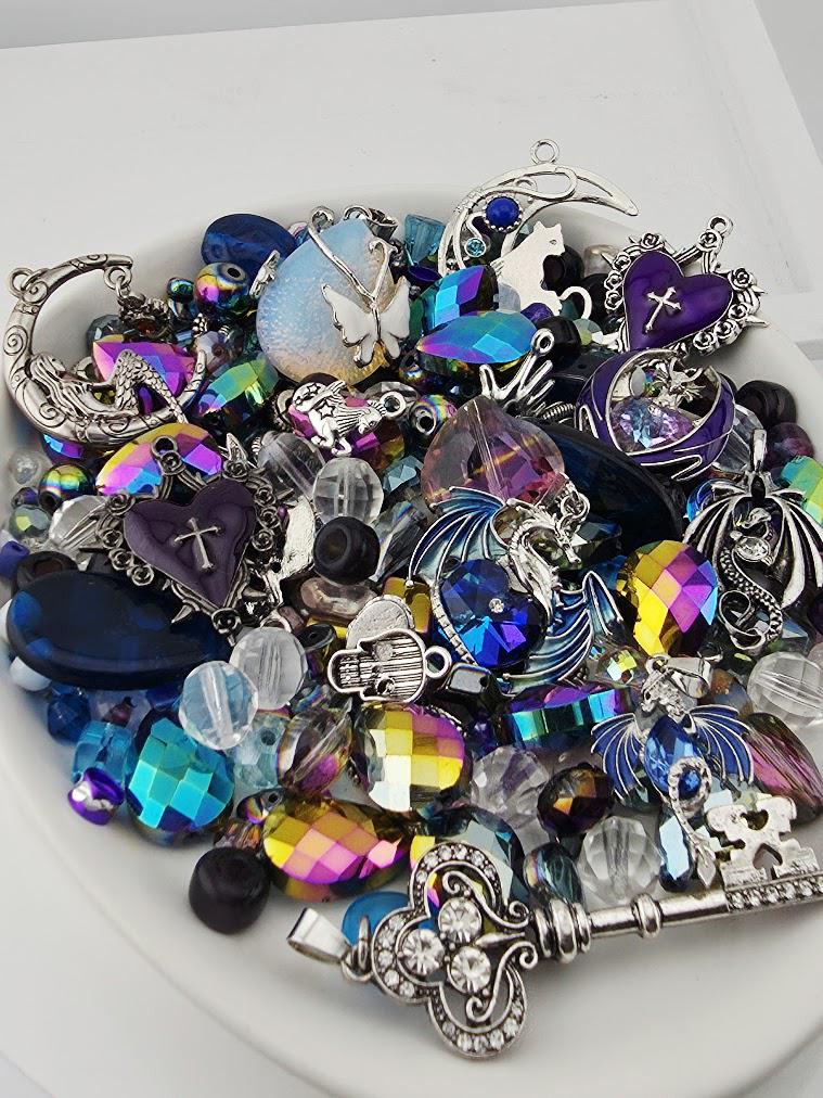 a variety of colorful and ornate jewelry pieces, including gemstones, charms, and pendants, arranged on a white surface.
