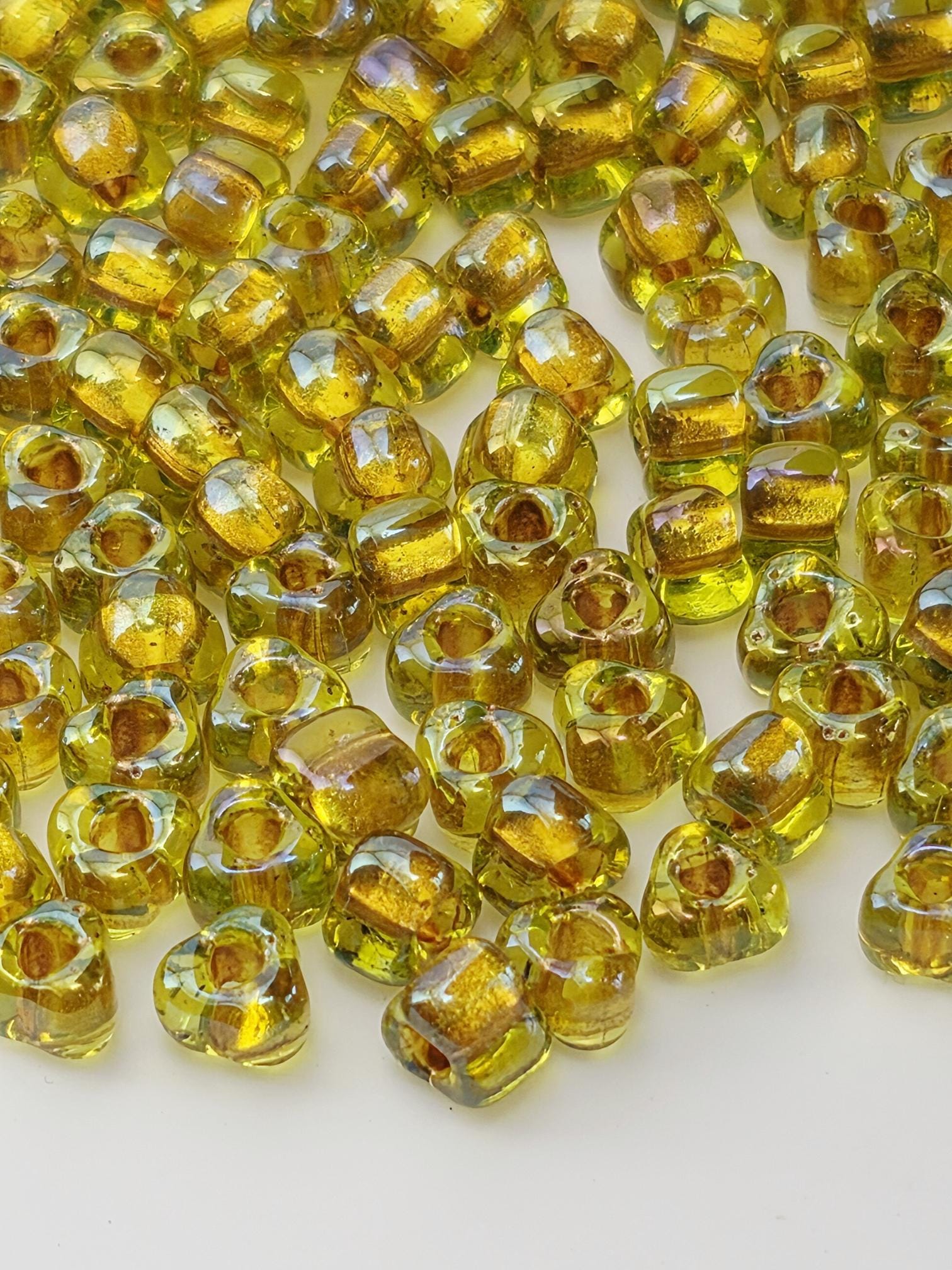 a close-up view of numerous small, clear glass beads in various shades of yellow, scattered across a white surface.