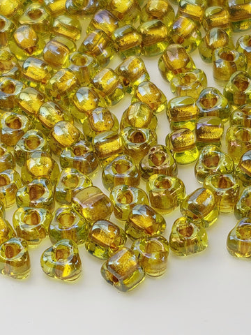 a close-up view of numerous small, clear glass beads in various shades of yellow, scattered across a white surface.