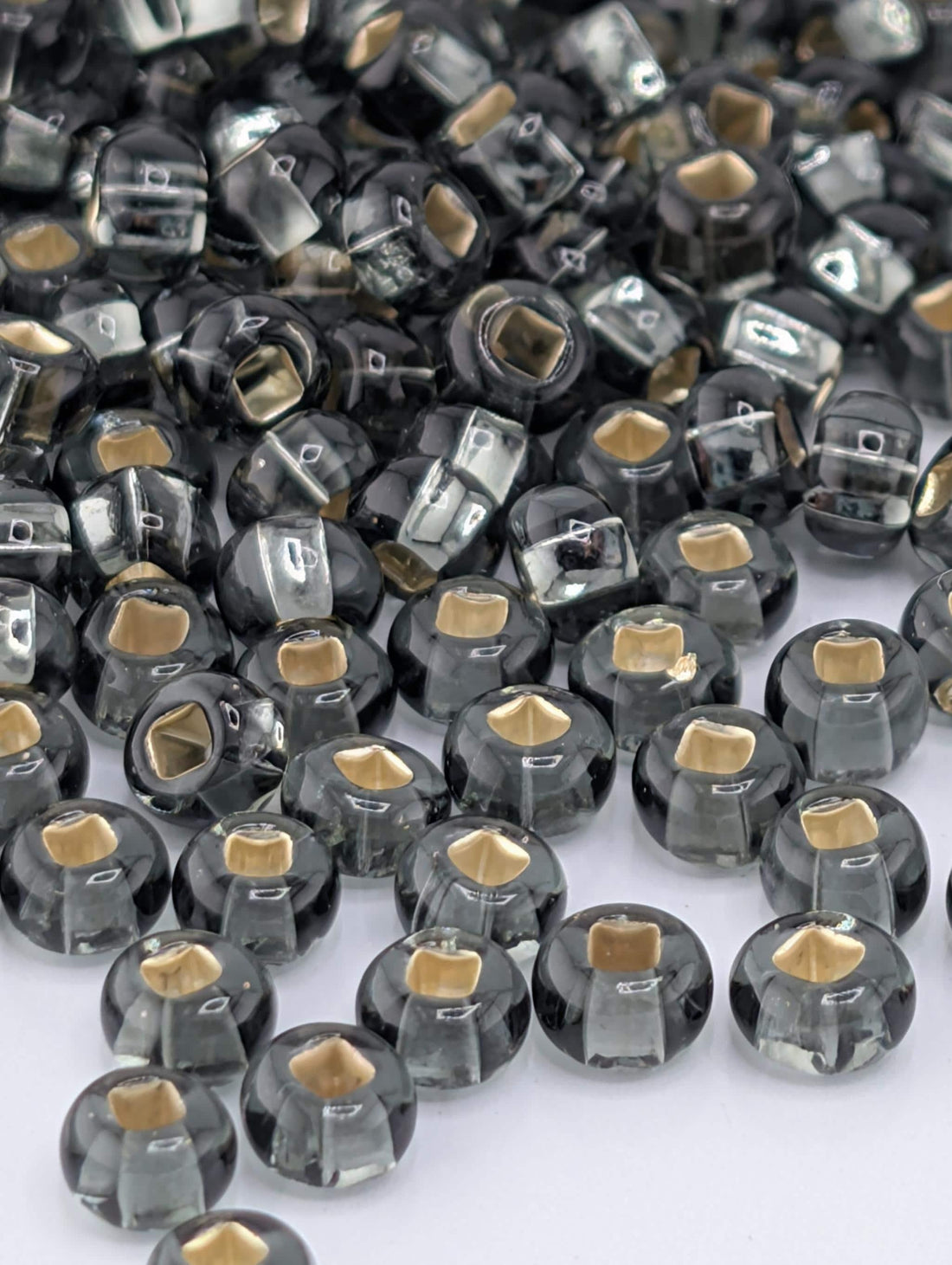 a collection of small, round, black and gold beads scattered across a white background.