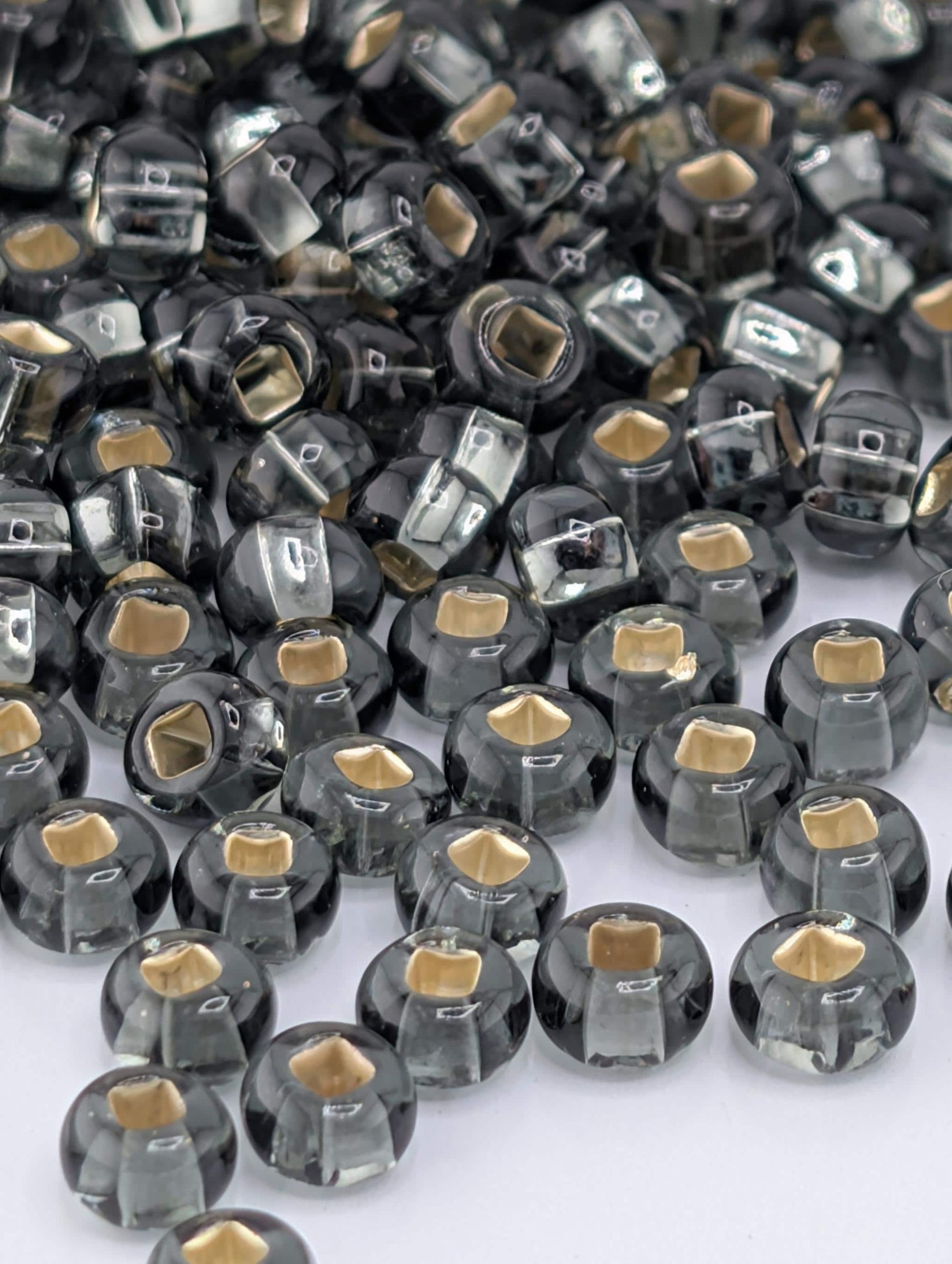 a collection of small, round, black and gold beads scattered across a white background.