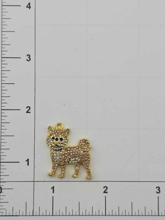 A gold-colored charm in the shape of a dog is shown on a ruler, indicating its size relative to the ruler's measurements.