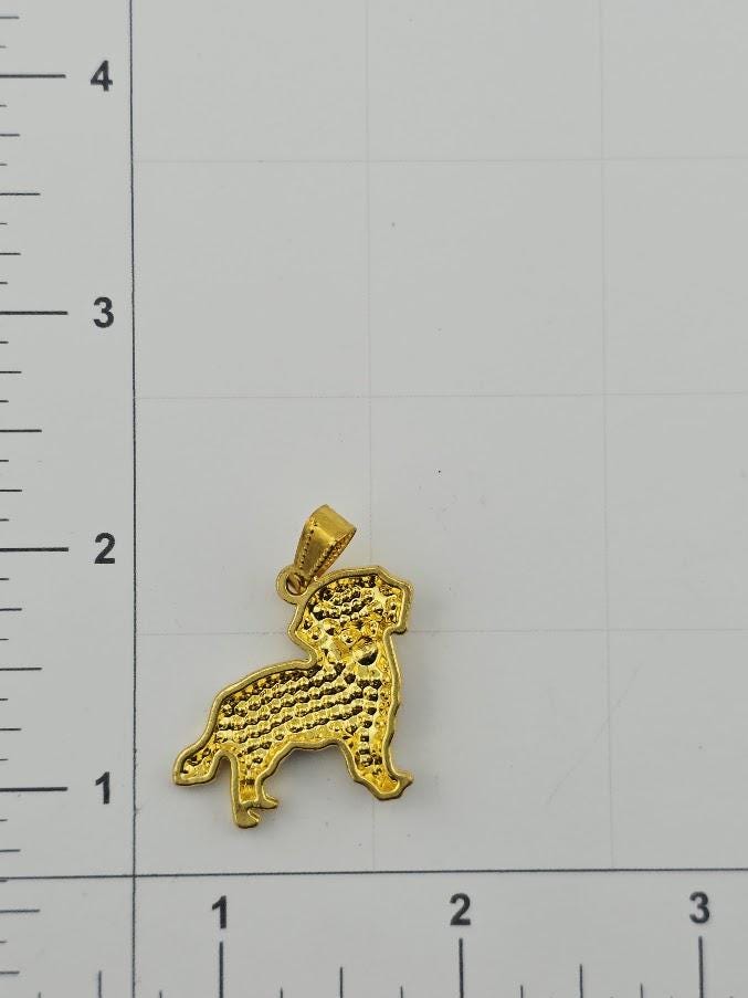 A gold-colored pendant in the shape of a dog is shown against a white background, with a ruler for scale.