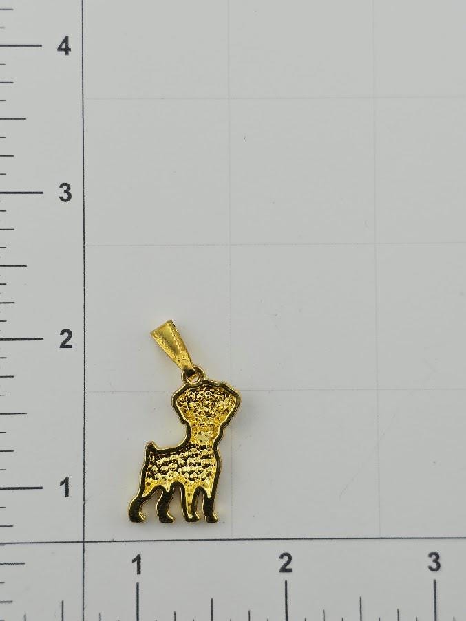 A small gold-colored pendant in the shape of a dog is shown against a white background with a ruler for scale.