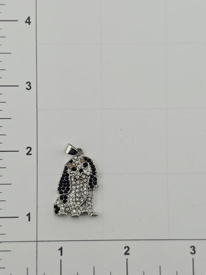 A pendant in the shape of a dog, made of silver and adorned with rhinestones, is shown against a white background with a ruler for scale.