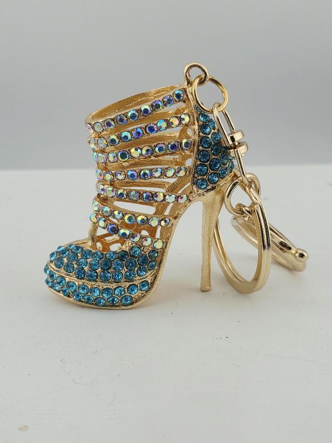 A gold-colored high-heeled shoe keychain with a blue crystal embellishment.