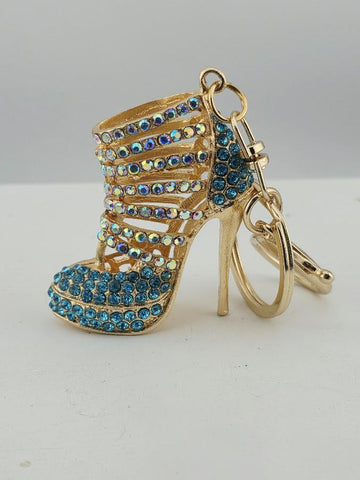 A gold-colored high-heeled shoe keychain with a blue crystal embellishment.