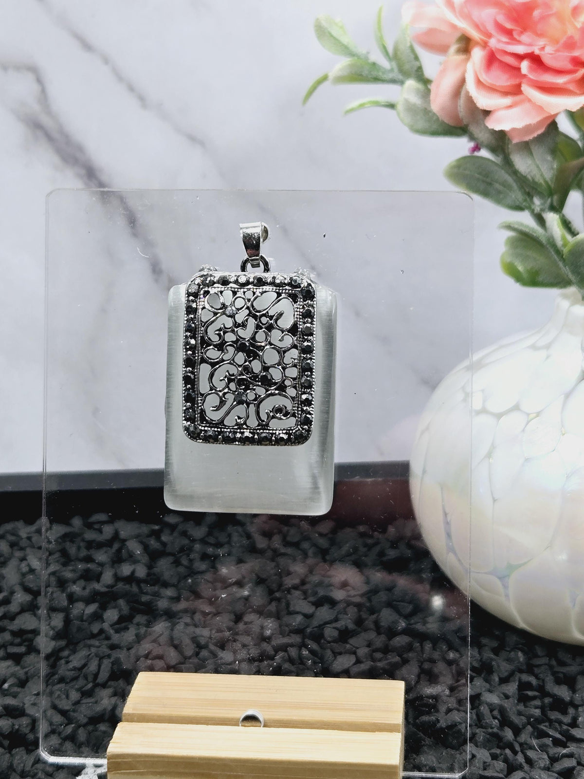 a pendant with a floral design, placed on a clear glass surface.