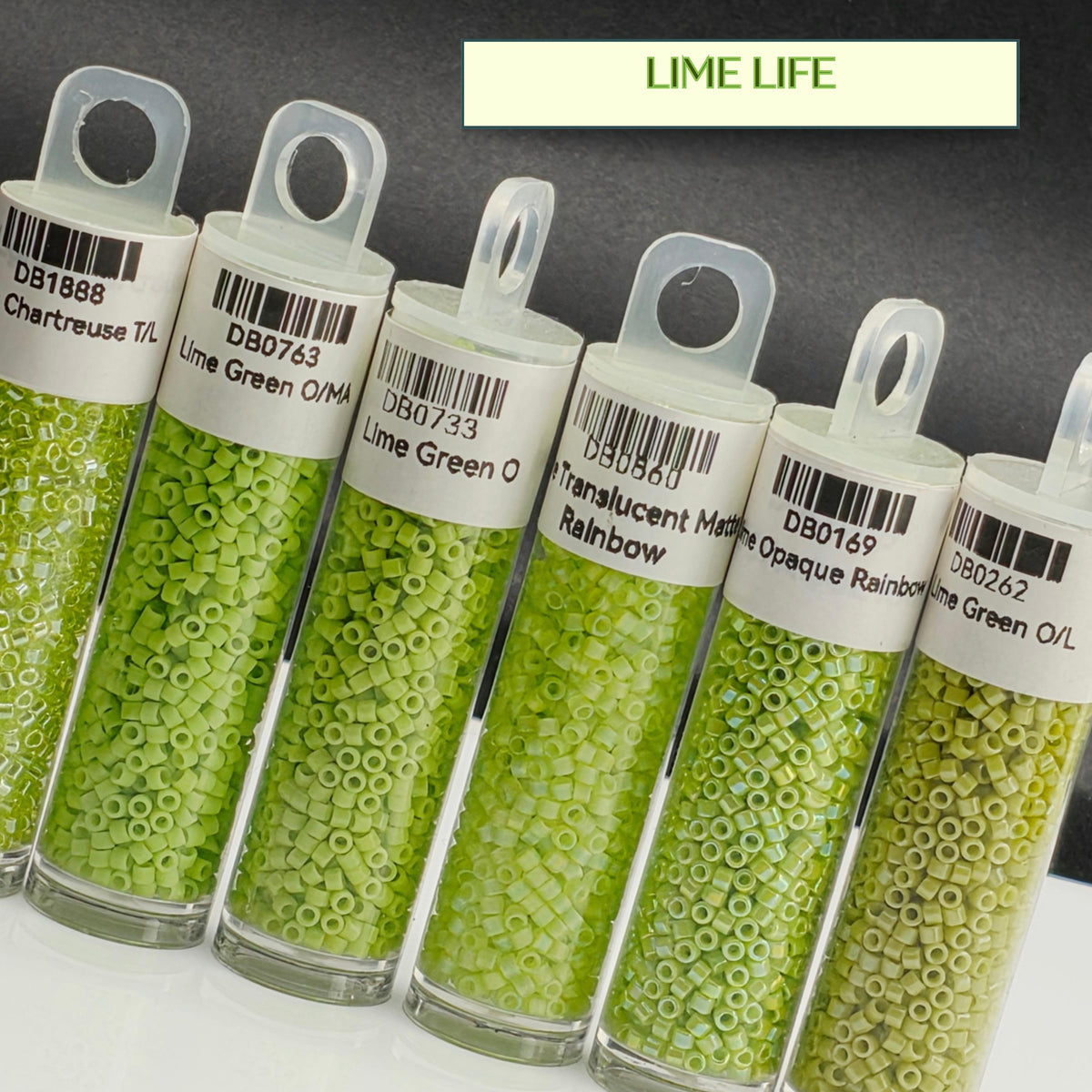 A collection of green beads in various sizes, each labeled with a different color, arranged in a row.