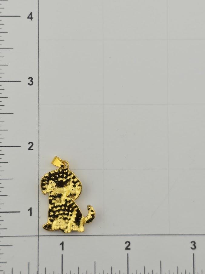 A gold-colored pendant in the shape of a dog is shown next to a ruler for size comparison.