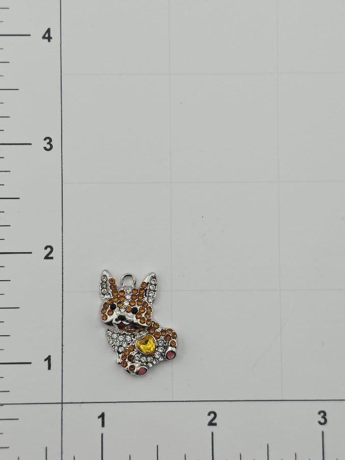 A small, colorful charm in the shape of a dog is shown on a ruler, indicating its size relative to the ruler's measurements.