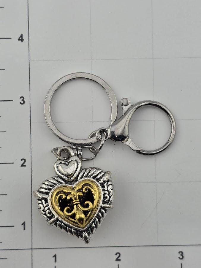 A heart-shaped keychain with a decorative metal design and a clasp.