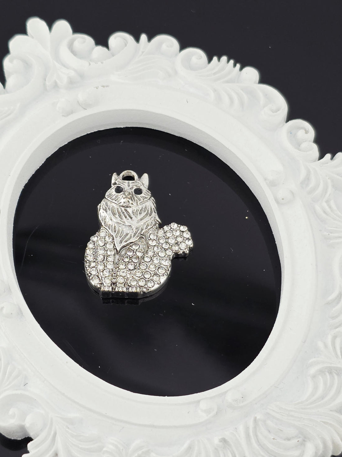 A silver pendant in the shape of a cat is displayed in a blue gift box with a white ribbon bow.