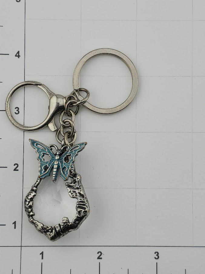 A keychain with a butterfly design and a clear crystal pendant.