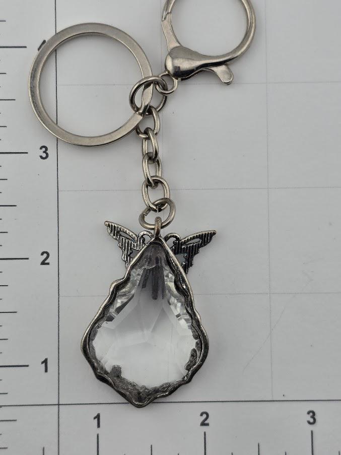 a clear crystal keychain with a metal clasp and wings attached to it.