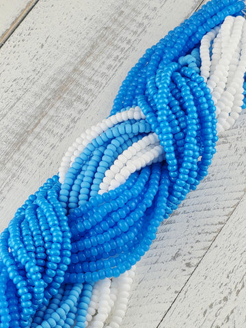 A close-up view of a collection of blue and white beads arranged in a twisted pattern on a wooden surface.