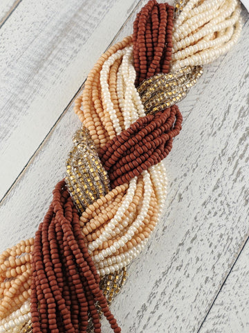 A collection of colorful beads, including white, brown, and beige beads, arranged in a braided pattern on a wooden surface.